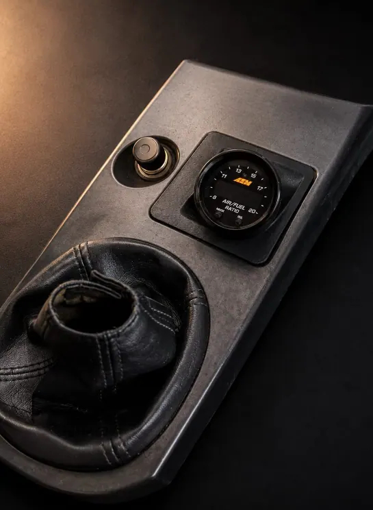 Mitsubishi Lancer Evo 7,8,9 ashtray console adapted to house an AEM air/fuel ratio gauge, shown beside the gear boot